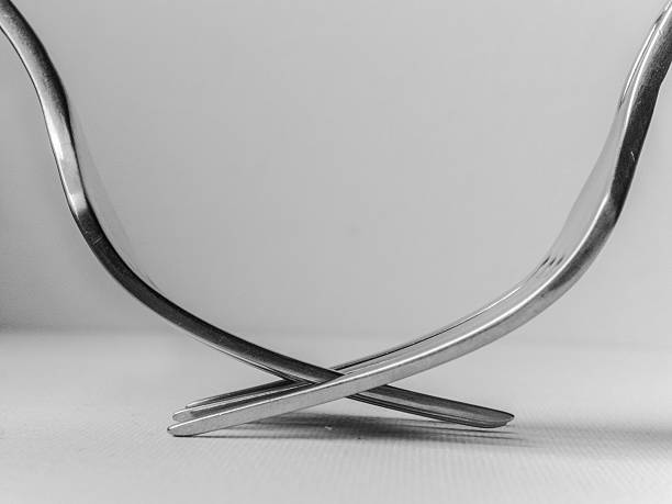 Two forks are crossed over each other, creating a unique and interesting design. Concept of creativity and playfulness, as the forks are not being used for their intended purpose of eating. Instead