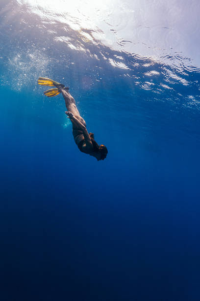 Beautiful woman relaxing and enjoying and playing underwater. She wears bikini and looks very attractive and graceful. Sunbeams coming from sea surface