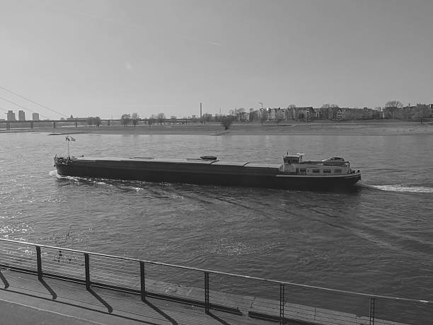 This photo was shot in late March 2025, by the Rhine river bank, on the downtown Dusseldorf Germany. Here is depicted a light weight barge slowly navigating upstream.