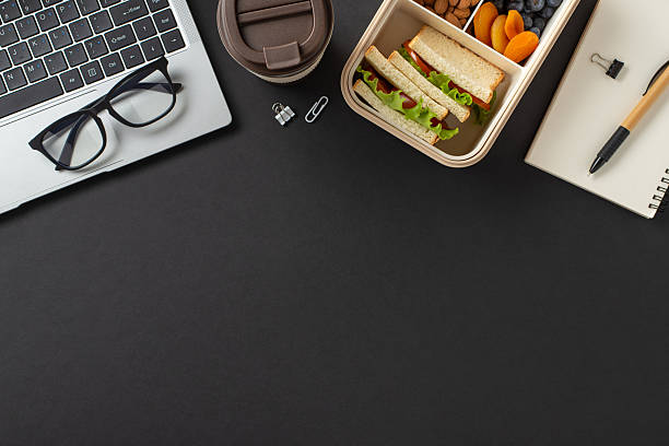 istock Overhead view features a laptop, glasses, notebook, and a bento box with snacks, ideal for workplace settings and remote work productivity 2207690365