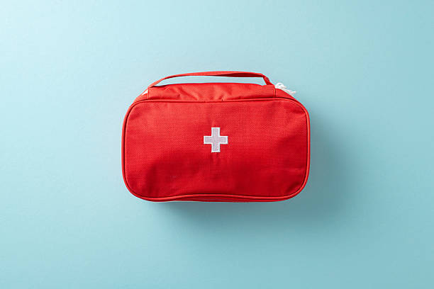istock Compact red first aid kit with white cross icon placed against a clean blue backdrop 2207690369