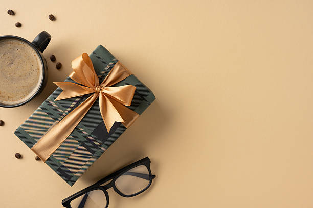 istock Decorative present box with a golden bow placed near coffee cup and eyeglasses 2207690375
