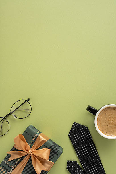 istock Flat lay vertical composition of a wrapped Father's Day gift, black polka-dot tie, coffee, and glasses against a green background 2207690378