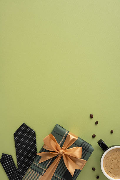 istock Gift wrapped with ribbon, coffee cup, and a decorative tie set on a vertical minimalist surface 2207690380