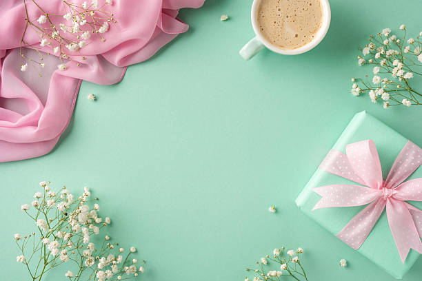 istock Flat lay composition featuring a mint-wrapped gift, delicate flowers, pink fabric, and coffee 2207690395