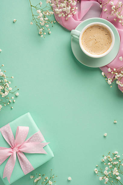 istock A delightful vertical flatlay featuring a green-wrapped present, a cup of coffee, delicate flowers, and a pastel-hued backdrop, evoking a sense of celebration, thoughtfulness, and cheerful elegance 2207690399
