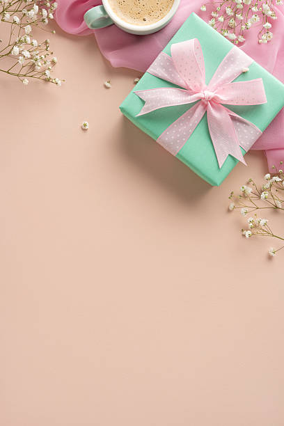 istock Vertical green gift box with a pink bow accompanied by coffee and flowers for occasions 2207690401
