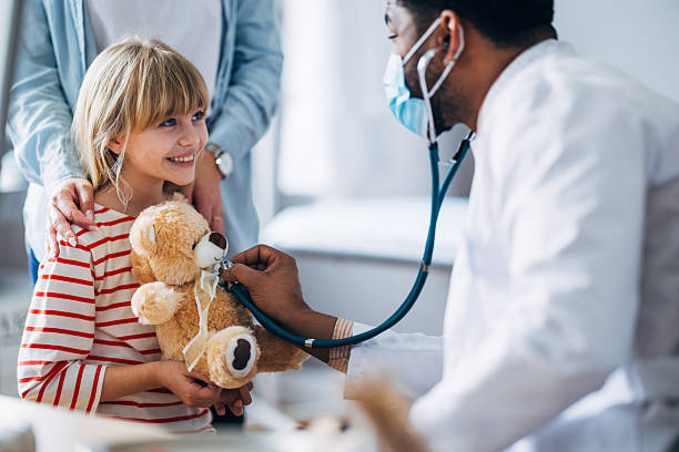 istock Doctor Using Stethoscope to Examine a Child Holding a Teddy Bear 2207690647