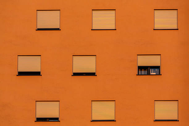 Orange apartment building facade with symmetrical windows and shutters