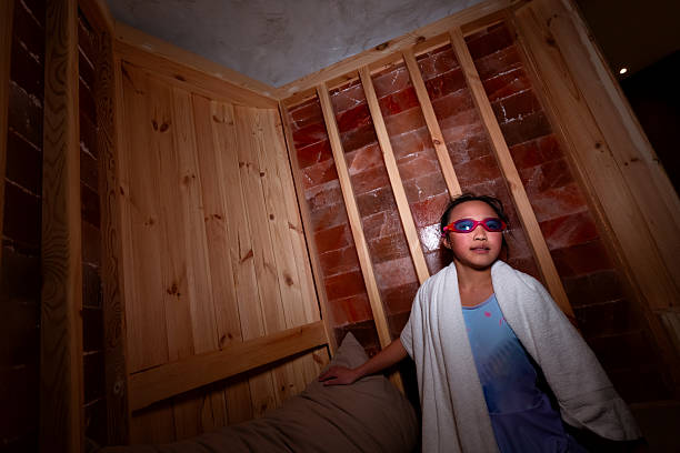 A little girl is relaxing in a spa-like salt cave, the room is filled with pinky Himalayan salt. it is said halotherapy is benefit for respiration conditions, skin conditions and allergies.