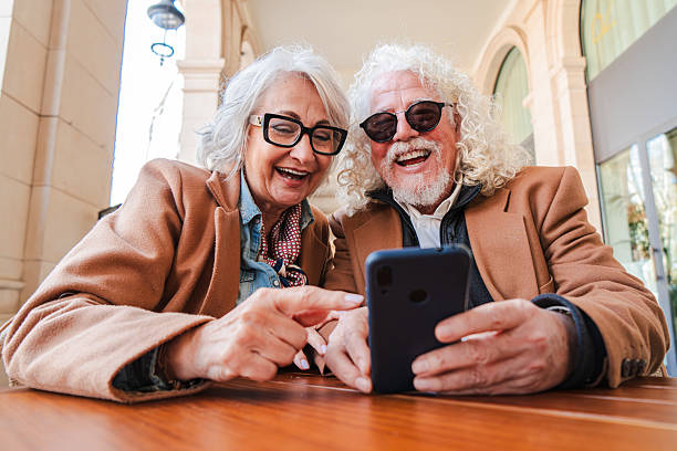 istock Joyful senior couple enjoying a delightful moment together while using a smartphone to explore apps and share laughter in a cozy outdoor cafe atmosphere with warm smiles and genuine connection 2207697626