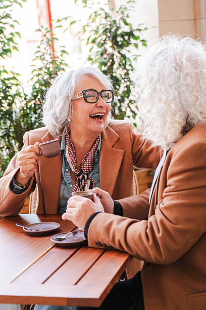 Joyful seniors sharing laughter and delightful moments over coffee while enjoying each other's company in a cozy cafe atmosphere filled with warmth and affection for one another, creating lasting memories