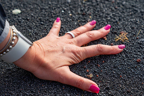 White woman hand with pink nails on black sand on the beach