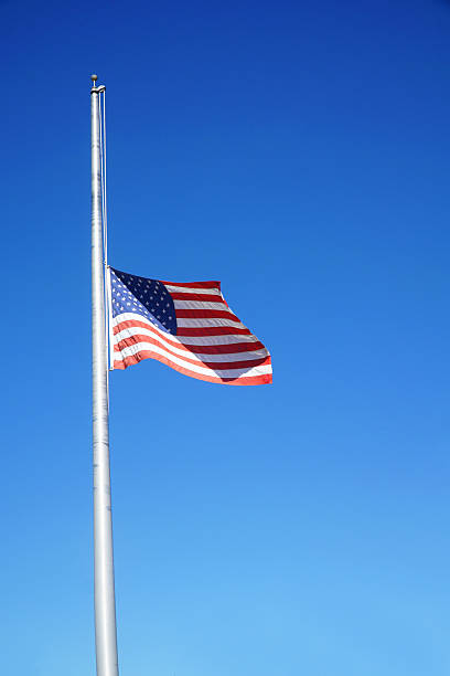 istock half mast American flag under blue sky 2207698989