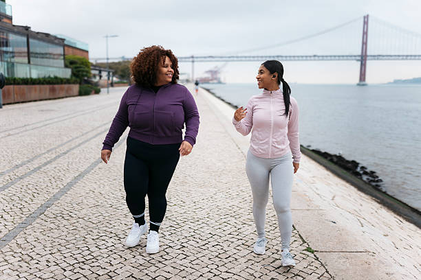 istock Two young women walking and talking by the river in Lisbon 2207701034