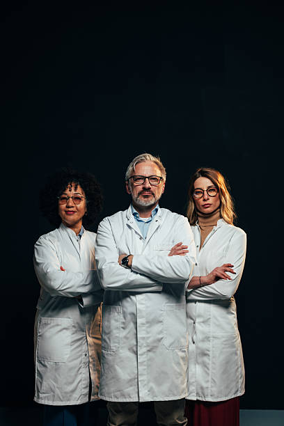 istock Three doctors confidently posing with arms crossed on black background 2207702973