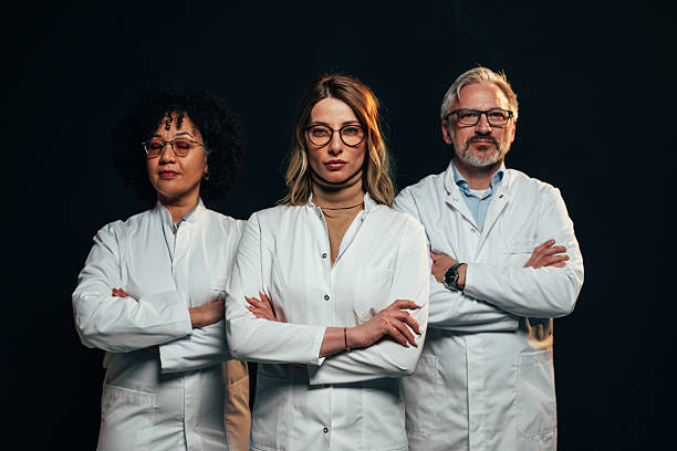 istock Three doctors confidently posing with arms crossed on black background 2207702976