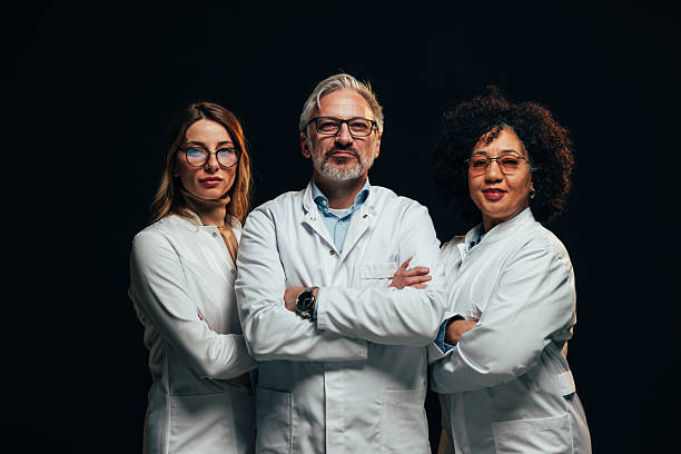 istock Three scientists posing with arms crossed on black background 2207703012