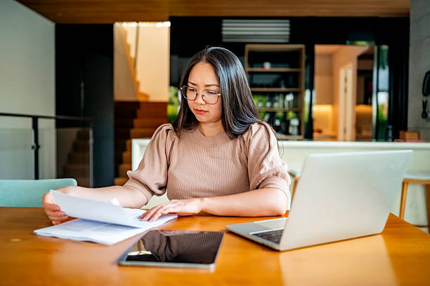 istock Focused Woman Reviewing Documents at Home Office Desk 2207703575