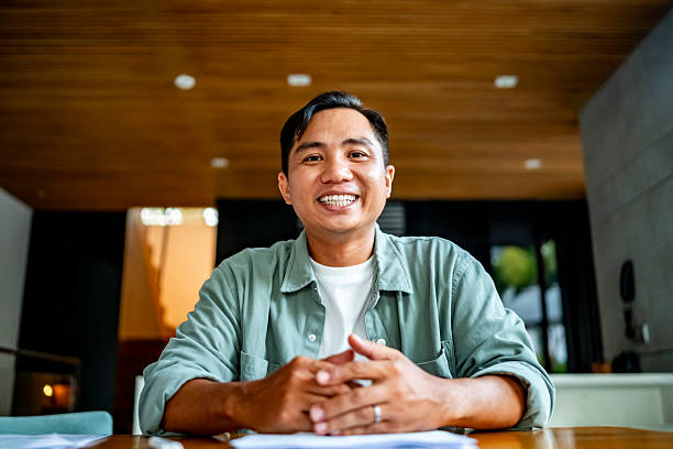 istock Smiling Man Sitting at a Wooden Table in Modern Home 2207703611