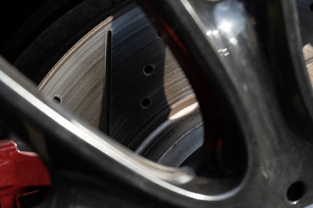 Detailing reveals a modern brake disc and wheel design, showcasing engineering precision in a high-performance vehicle during daylight conditions