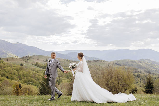 istock A bride and groom are walking on a grassy hillside 2207710372
