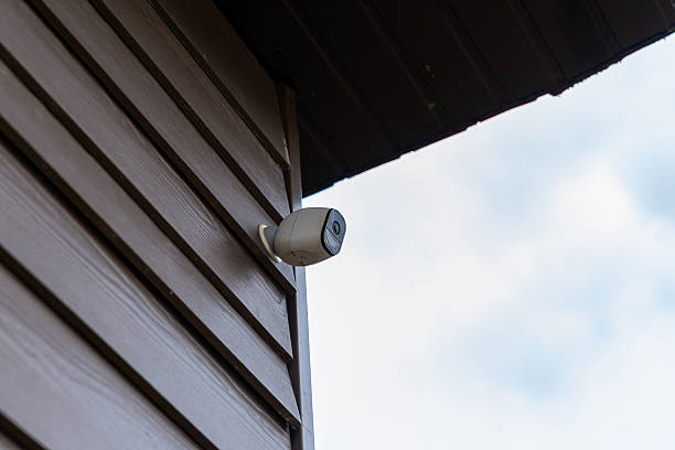 istock Security Camera on Wooden Wall of Private House with Cloudy Sky 2207710817