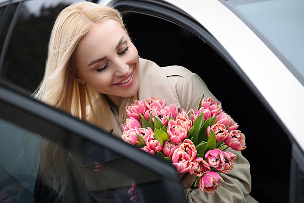 istock Happy young woman with beautiful bouquet in car 2207711029