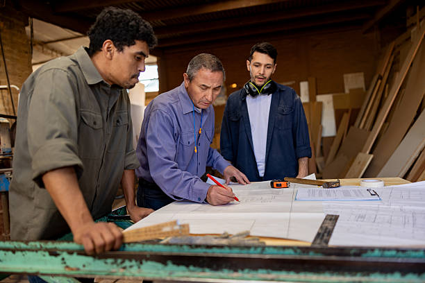 carpenter explaining a design to a couple of workers at a woodshop - outdoor furniture manufacturers 個照片及圖片檔