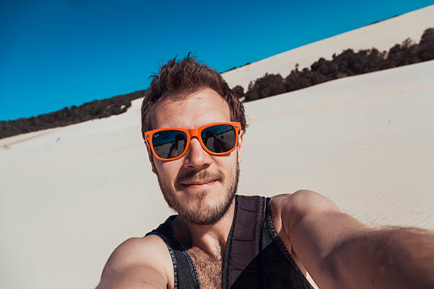 istock Adventurer enjoys sunny day at scenic sand dunes while taking a cheerful selfie 2207716633