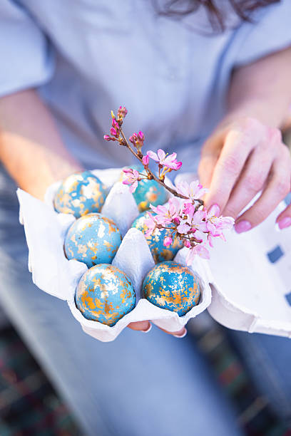 Woman Holding Naturally Dyed Easter Eggs with Gold Foil and Spring Blossoms