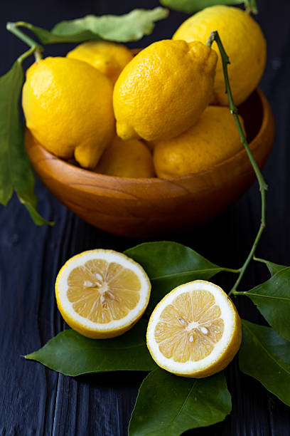 istock Fresh Lemons While and Halved with Green Leaves on Dark Wooden Background 2207717403