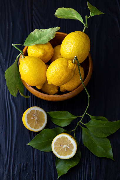istock Fresh Lemons While and Halved with Green Leaves on Dark Wooden Background 2207717414