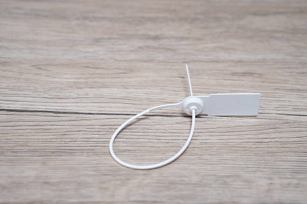 White plastic seal on wooden background. Plastic seal for sealing valuable goods and parcels. Logistics concept.