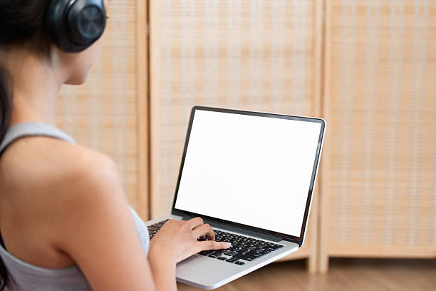 Seated comfortably, a woman engages with her laptop, deeply focused and absorbing information while enjoying her headphones, creating a productive atmosphere.