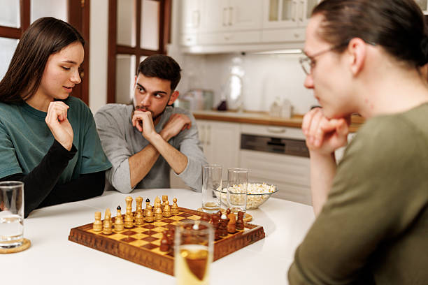 istock Young couple sitting at the table and playing chess together at home 2207723105