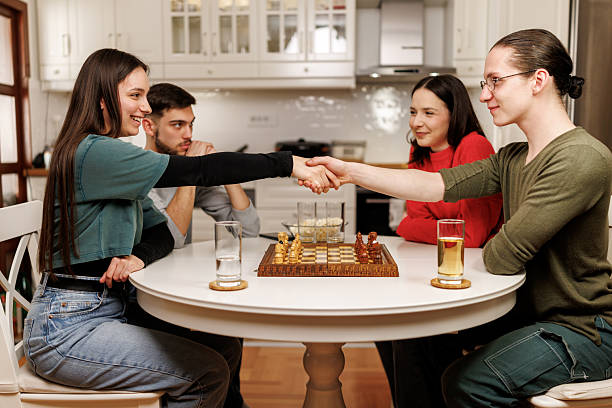 Friends handshaking over chess board before the game