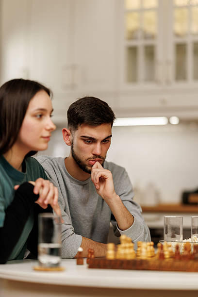 istock Young couple sitting at the table and playing chess together at home 2207724126