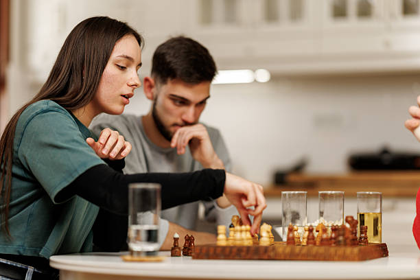 istock Young couple sitting at the table and playing chess together at home 2207724239