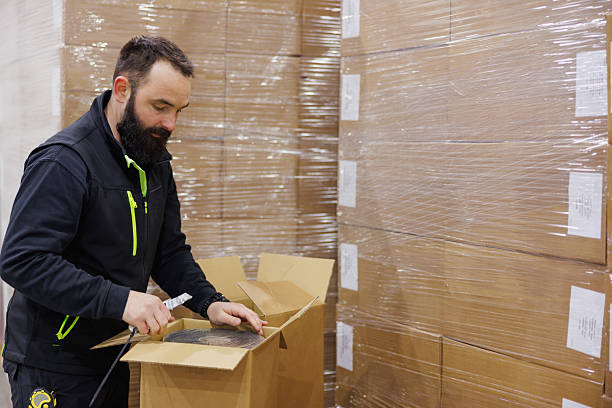 istock Working in distribution warehouse, opening cardboard box of electrical insulation tape 2207729677