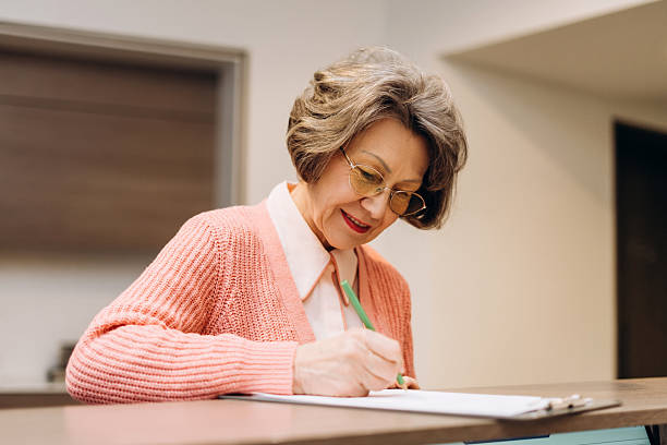 istock Senior woman filling out documents at desk with focused concentration 2207730783
