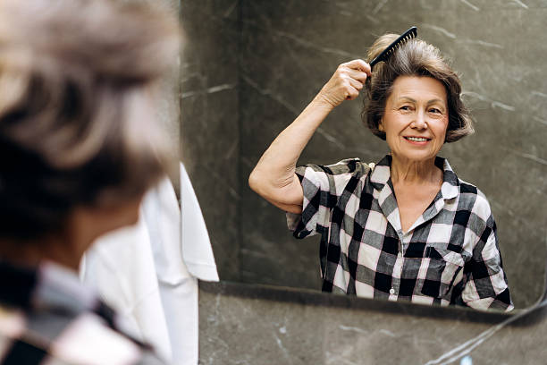 istock Mature woman combing hair in bathroom mirror 2207730801