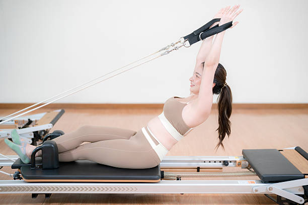 istock Active woman performing Pilates exercises on a reformer bed. 2207733624