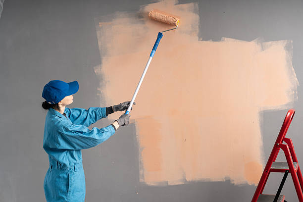istock female artist paints wall with paint roller. 2207736743