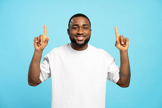 istock Smiling African American man pointing up with index fingers on blue background 2207737476