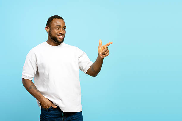 istock Smiling African American man pointing finger showing something on blue background 2207737485