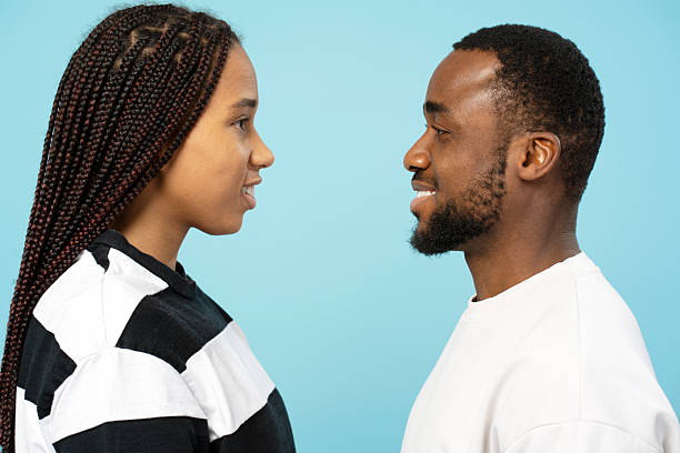 istock Young couple smiling and looking at each other on blue background 2207741290