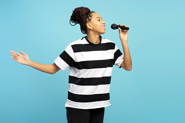 istock Beautiful smiling African American singer performing with microphone on blue background 2207741923