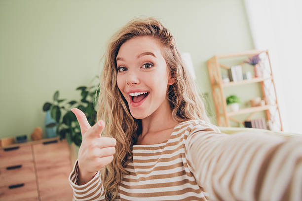istock Joyful young woman at home pointing playfully in a striped pullover while enjoying a relaxed weekend indoors 2207742127