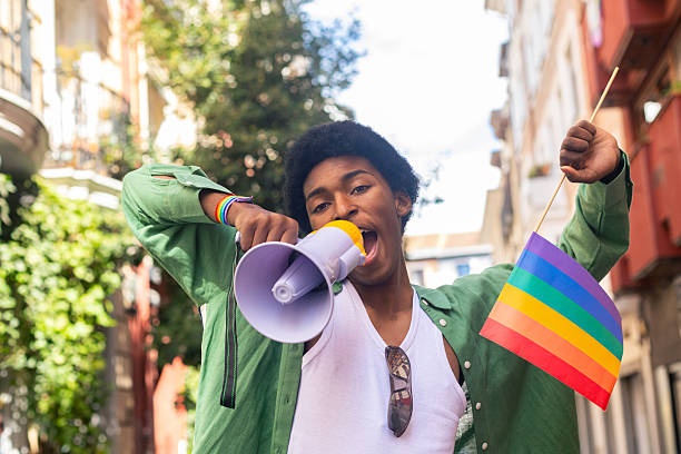 istock Young activist shouting with megaphone at pride parade promoting lgbtq plus rights 2207743454